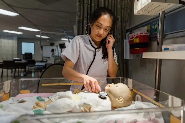 A nursing student at Concordia University Irvine examines a synthetic baby doll in a hospital setting.