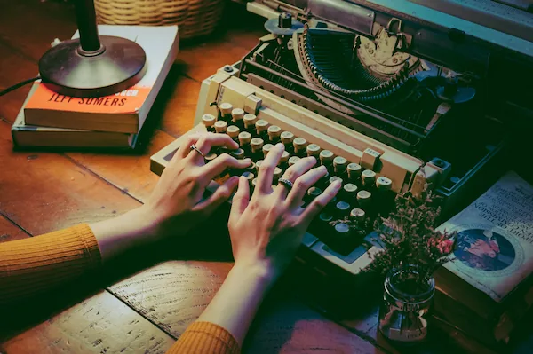 Image of hands typing on a retro typewriter.