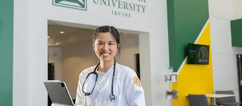 A nurse smiling and holding a laptop at Concordia University Irvine