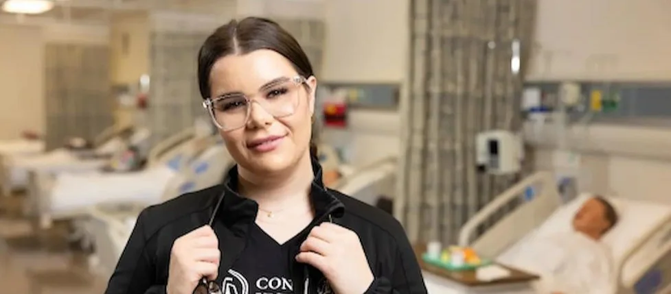 A nurse in a hospital room with a stethoscope around her neck