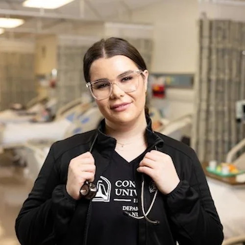 A nurse in a hospital room with a stethoscope around her neck