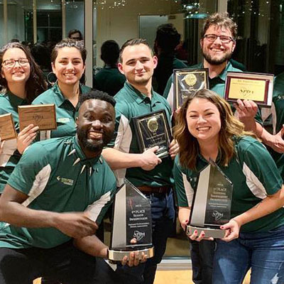 Members of the CUI Debate team hold plaques and award trophies they won at the National Parliamentary Debate Association Championship Tournament in March 2019.